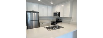 a kitchen with white cabinets and a sink and a refrigerator